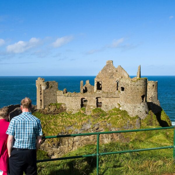 Couple admiring the view of the castle on the cliff-edge and sea in the background.