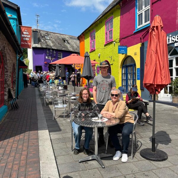 Two ladies and man sitting outside a coffee shop.