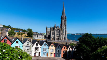 A photo taken onthe hill above Cobh. Cathedral in the background, row of colourful houses in front of it, know as the Stack of Cards. Sunny day.