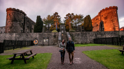 People in front of Cork City Goal at sunset. Old stone building.
